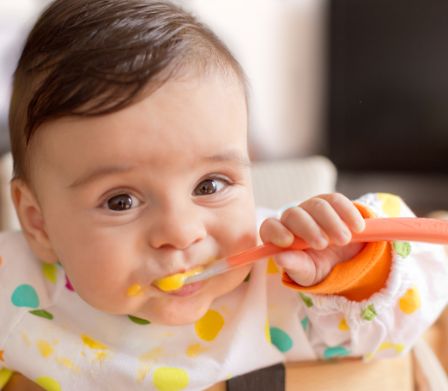 Baby isst Brei mit einem Kinderlöffel