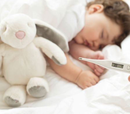 Il bebè dorme con il coniglietto di peluche - il termometro indica 38 gradi