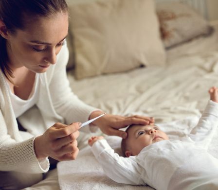 Maman avec bébé tenant un thermomètre médical dans la main