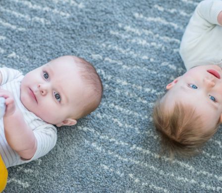 Zwei Babys auf dem Spielteppich