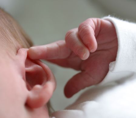 Bébé touche son oreille avec la main