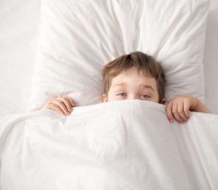 Un bambino si nasconde sotto le coperte