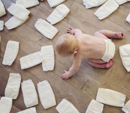 Ein Baby krabbelt zwischen vielen Windeln auf dem Boden