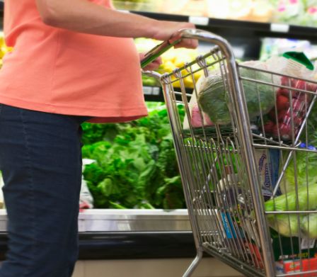 Femme enceinte en train de pousser un chariot dans un supermarché