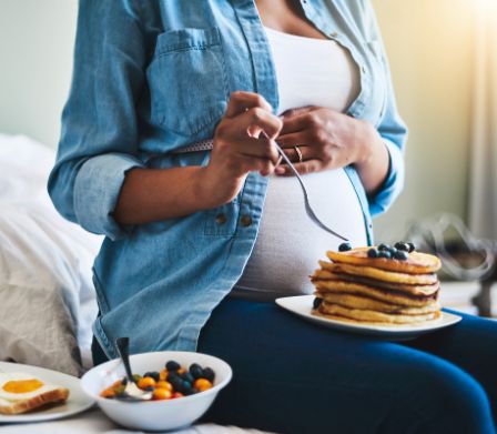 Schwangere isst mit Genuss Pancakes