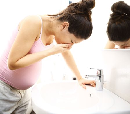 Femme enceinte en train de se pencher sur un lavabo dans la salle de bain