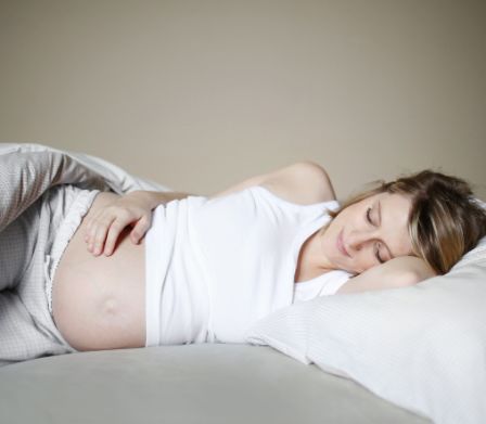 Donna incinta a letto sdraiata su un fianco
