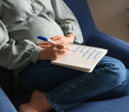 Schwangere mit Namenszettel auf dem Bauch