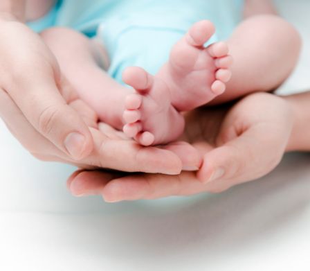 Kleine Babyfüsschen in den Händen der Mutter