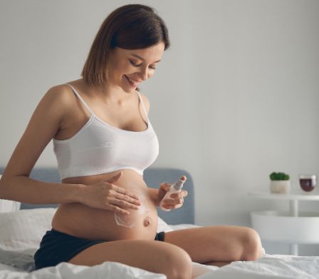 Femme enceinte appliquant de la crème sur son ventre