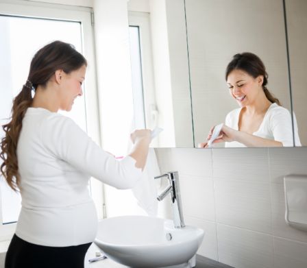 Schwangere mit Zahnbürste im Badezimmer