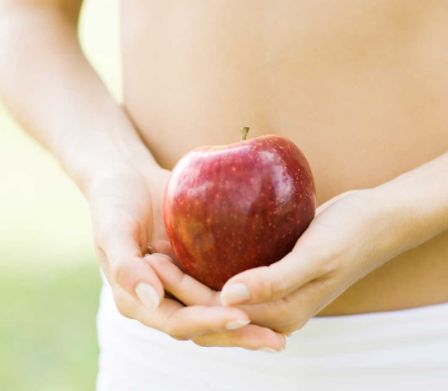 Frau mit Apfel vor dem Bauch