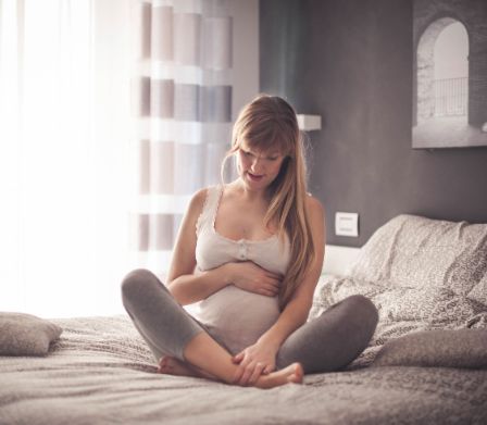 Donna incinta seduta sul letto