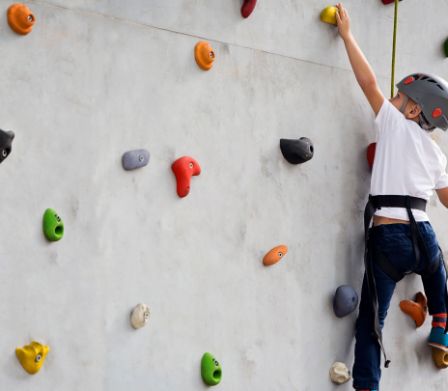 Un ragazzo si arrampica su una parete da arrampicata