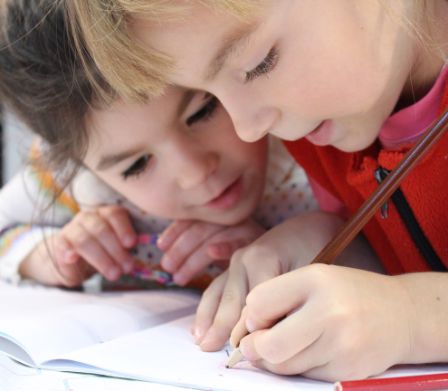 Zwei Kinder zeichnen in einem Heft