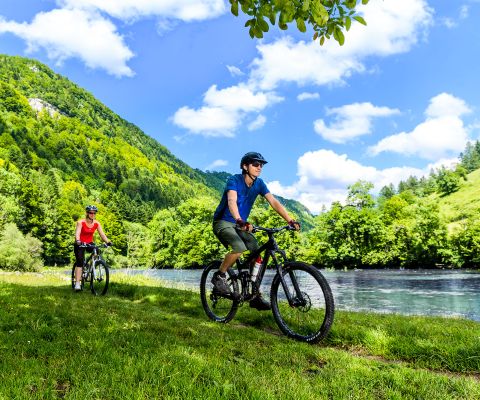 Couple sportif longeant la rivière à vélo dans le Jura