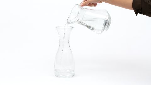 Eine Glasflasche mit einem Viertel Leitungswasser füllen