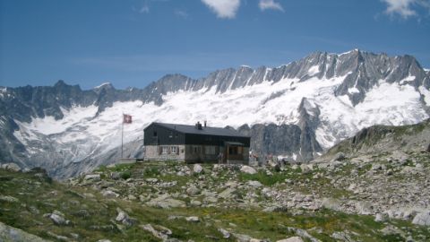 SAC Hütte vor schneebedecktem Alpenpanorama