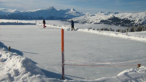 Pista di ghiaccio naturale Alp Raguta davanti al panorama delle Alpi
