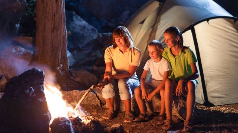 Mutter mit zwei Kindern sitzen vor einem Lagerfeuer Mutter mit zwei Kindern sitzen vor einem Lagerfeuer