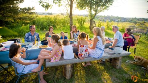 Famiglia seduta a un lungo tavolo in giardino Famiglia seduta a un lungo tavolo in giardino